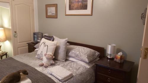 a teddy bear sitting on a bed with pillows at Rural Farmhouse in Poughill