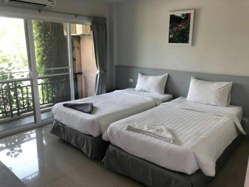 two beds in a hotel room with a balcony at Rose Villa Hote in Pak Chong
