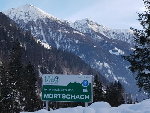a sign in front of a snow covered mountain at Tattoo PENSION mit Restaurant und Tattoo-Studio in Mörtschach