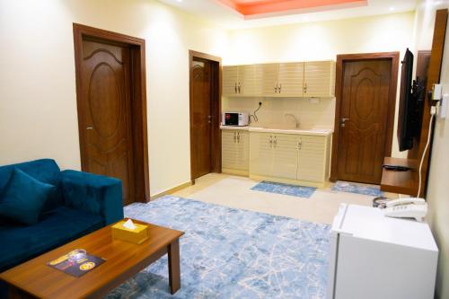 a living room with a blue couch and a kitchen at فندق بــــاســــيل in Hafr Al Baten