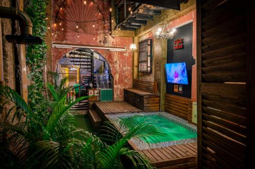 una piscina cubierta en una habitación con TV y plantas en The Clock Hostel & Suites, en Cartagena de Indias