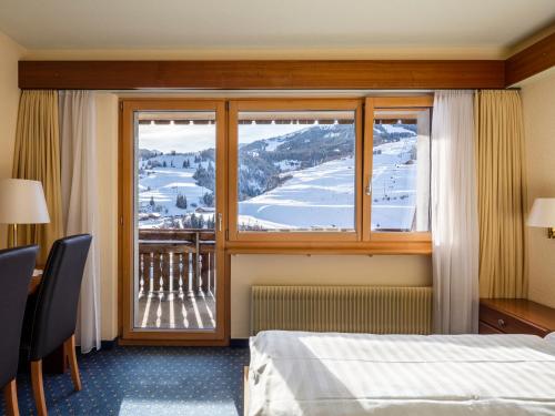 ein Hotelzimmer mit einem Bett und einem Fenster in der Unterkunft DANILO Savognin in Savognin