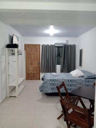 a room with two beds and a table and a refrigerator at Kitnet 2 mobiliada centro de Torres RS, a 600m Da Praia Grande in Torres