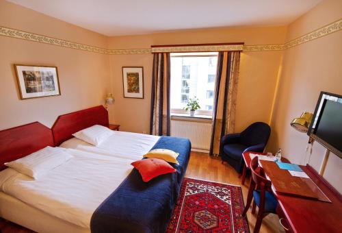 a bedroom with a bed and a desk and a television at Hotel Örgryte in Gothenburg