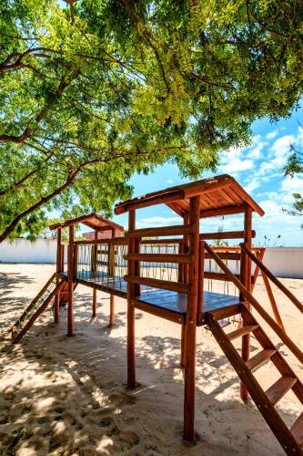 a wooden bench sitting under a tree on the beach at Pousada Iguana in Canoa Quebrada