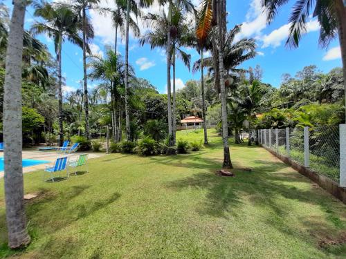 a yard with palm trees and a swimming pool at Recanto dos Passaros in Socorro