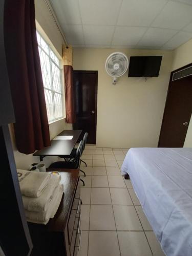 a room with a bed and a desk and a fan at Kira's House in Piura