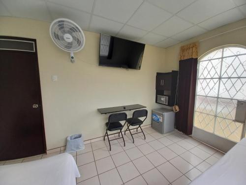 a room with a kitchen with two chairs and a fan at Kira's House in Piura