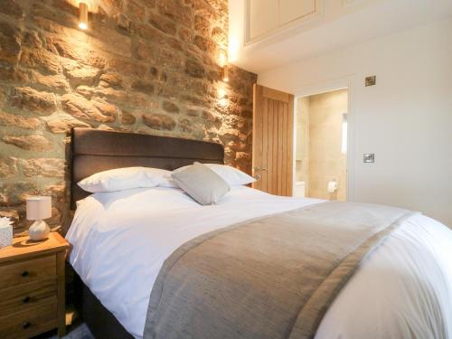 a bedroom with a large bed with a stone wall at Shepherd's Crook in Harrogate