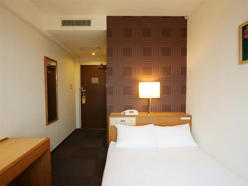ein Schlafzimmer mit einem Bett, einem Schreibtisch und einer Lampe in der Unterkunft Smile Hotel Towada in Towada