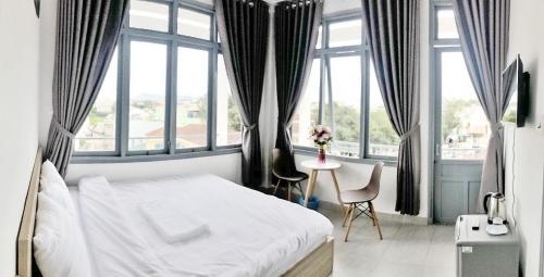 Schlafzimmer mit einem Bett, einem Tisch und Fenstern in der Unterkunft M Hotel Đà Lạt in Da Lat