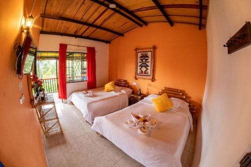 two beds in a room with orange walls at Hotel Alto de los Andaquies in San Agustín