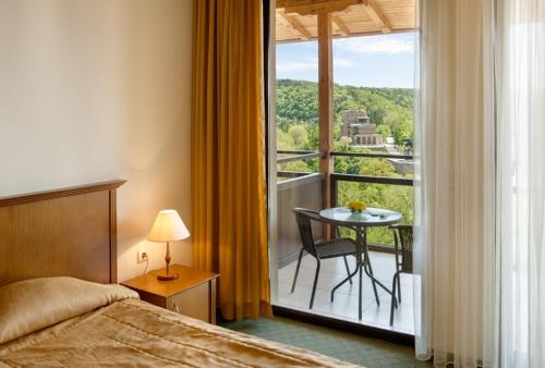 a bedroom with a bed and a balcony with a table at Hotel Panorama in Veliko Tŭrnovo
