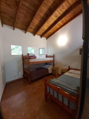 1 dormitorio con 2 camas y techo de madera en Hostel Meridiano 71 en El Bolsón