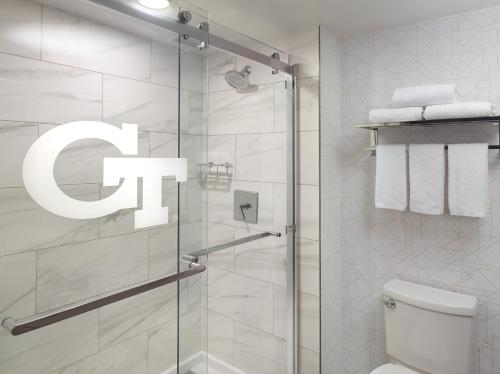 a bathroom with a shower with a toilet and a sign at Georgia Tech Hotel and Conference Center in Atlanta