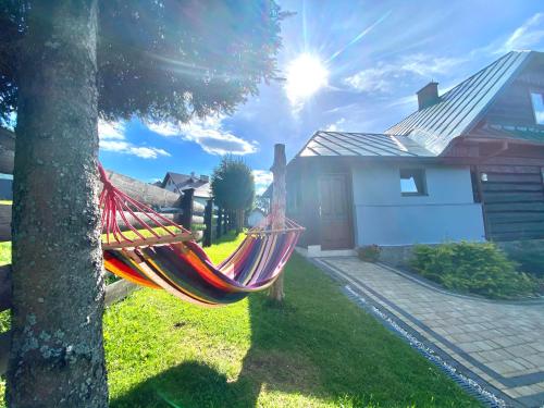 a hammock hanging from a tree in front of a house at Osada Koniaków 4 in Koniaków
