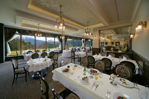 a dining room with white tables and chairs and windows at Apartmány PRESTIGE Donovaly in Donovaly