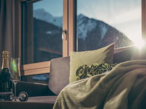 a person laying in bed with a glass of wine at LENZup Apartments in Mayrhofen