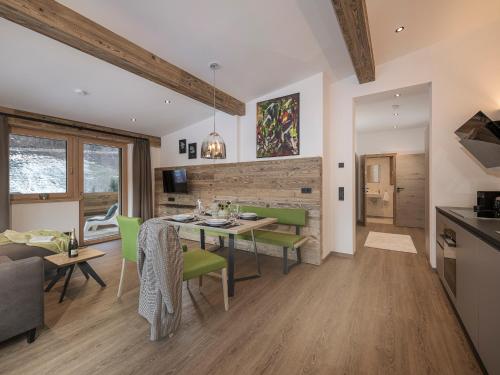 a kitchen and dining room with a table and green chairs at LENZup Apartments in Mayrhofen