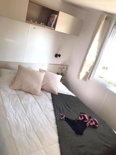 une petite chambre avec un lit avec des draps blancs et des oreillers dans l'établissement Bungalow paisible à Saint-Jean-de-Monts avec piscine partagée, à Saint-Jean-de-Monts