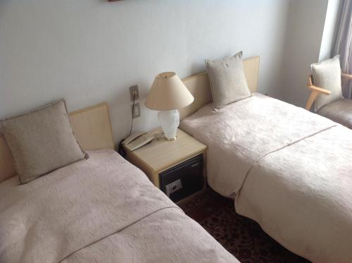 a hotel room with two beds and a lamp on a table at Yamaichi Bekkan in Miyajima