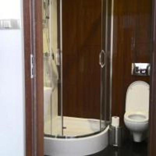 a bathroom with a glass shower with a toilet at Aparthotel Łódź 55 Piotrkowska in Łódź