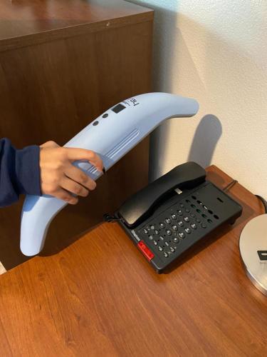 a person holding a hair dryer next to a phone at Sterling Inn in Santa Clara