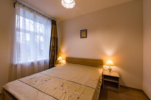 a bedroom with a bed with a window and two lamps at Allegro in Liepāja