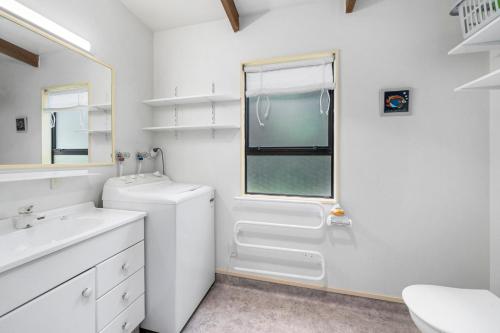 a white bathroom with a toilet and a sink at Waimea Cottage - Waikanae Holiday Home in Waikanae