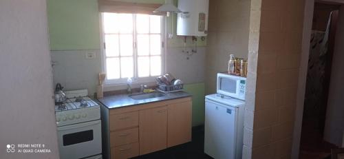 una cucina con lavandino, piano cottura e forno a microonde di Cabaña en las sierras de Córdoba a Valle Hermoso