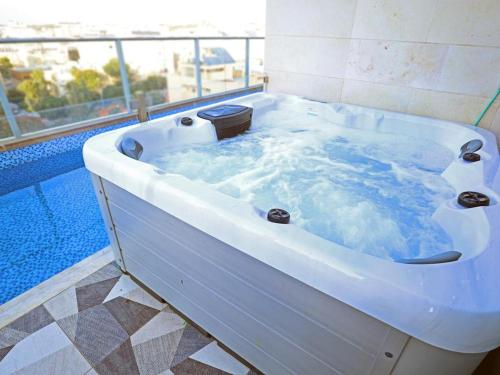 Luxury Rooftop Apartment in Netanya في نتانيا: حوض استحمام أبيض ممتلئ بالماء في الحمام