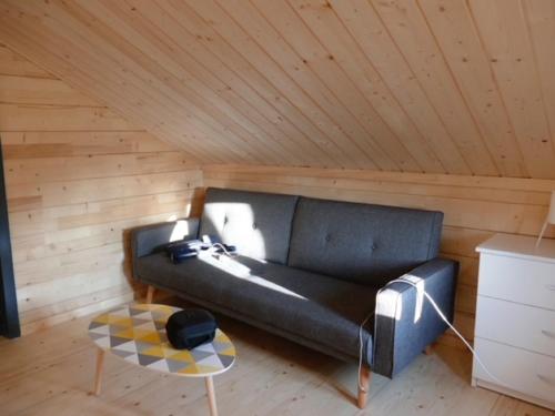 Sofá negro en una habitación con techo de madera en Chalet in Saint Laurent on a slope, en Saint-Laurent-du-Jura