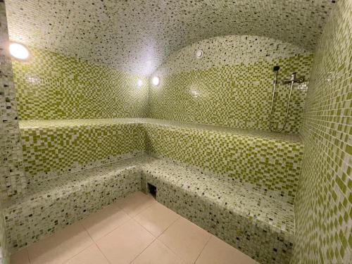 y baño de azulejos verdes con ducha y bañera. en Juna Aqua Life, en Estosadok