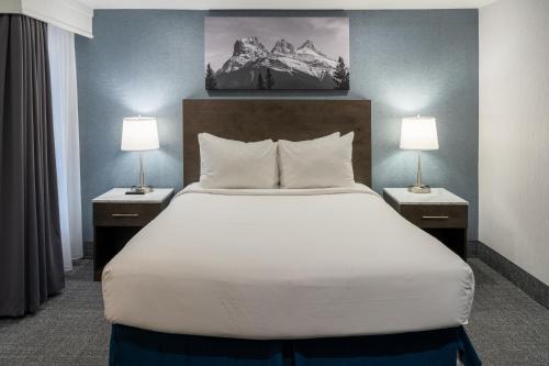 een bed in een hotelkamer met 2 lampen bij Red Carpet Inn in Banff