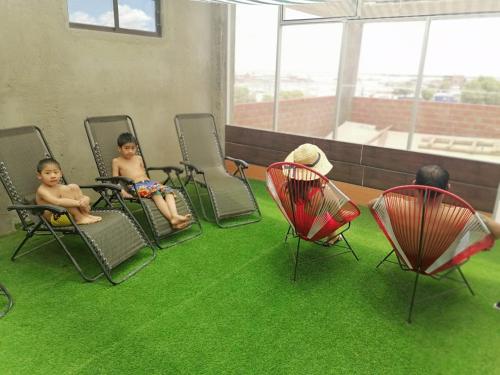 two children sitting in chairs on artificial grass at Casa de Sal - Salt Hotel in Uyuni
