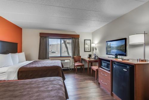 a hotel room with two beds and a flat screen tv at AmericInn by Wyndham Coon Rapids in Coon Rapids