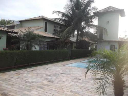 uma casa com uma palmeira e uma entrada de tijolos em Linda casa para temporada no Peró/Cabo Frio em Cabo Frio