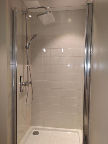 une douche avec une porte vitrée dans une salle de bain dans l'établissement La cachette d'Anne-Charlotte (jardin, parking dans la campagne Honfleuraise), à Fourneville