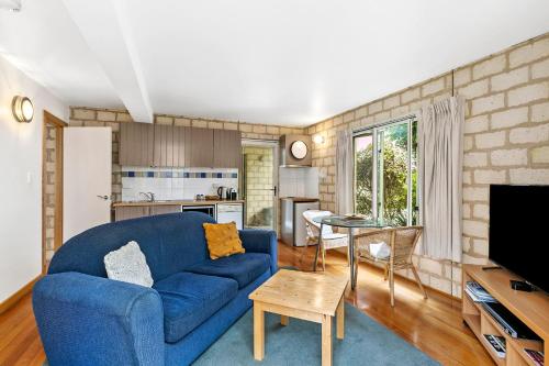 a living room with a blue couch and a kitchen at Seahaven Village in Barwon Heads