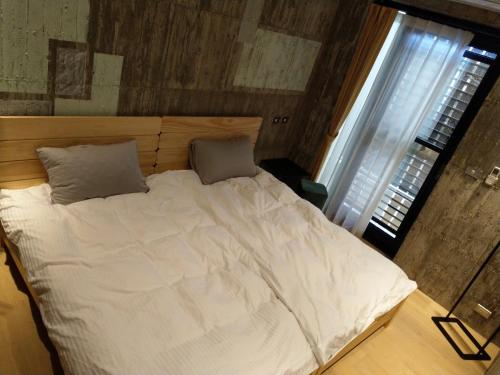 a large white bed with two pillows in a bedroom at 350 Lodge in Taitung City