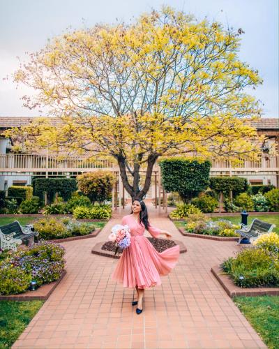 a woman in a pink dress holding a bunch of flowers at Mercure Canberra in Canberra