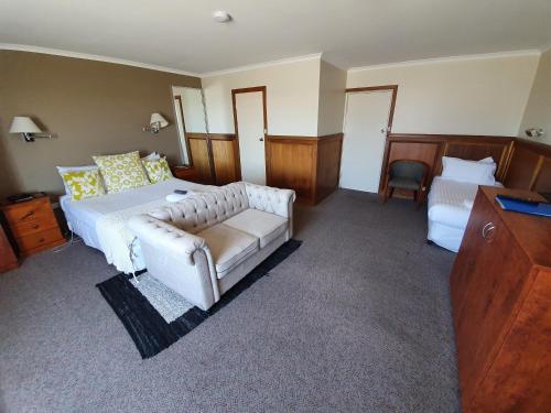 a bedroom with a white bed and a couch at Robe Haven Motel in Robe