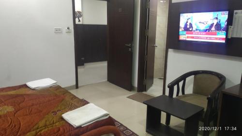 a bedroom with a bed and a tv and a chair at Hotel Popular in Amritsar