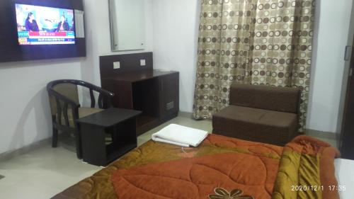 een slaapkamer met een bed en een stoel en een tv bij Hotel Popular in Amritsar