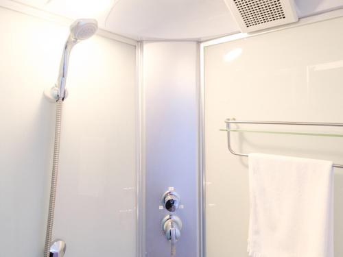 a shower with a glass door and a towel at Hotel Shionnoumi in Miyako Island