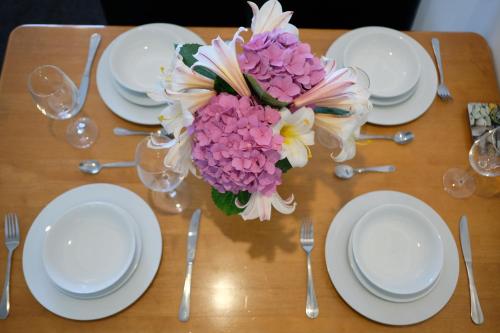 a table with white plates and a vase of flowers at Montana Lodge Motel in Blenheim
