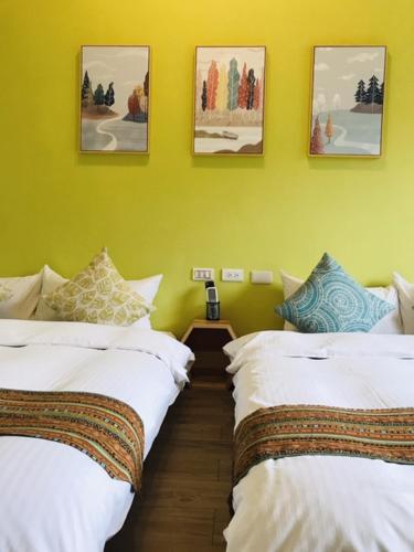 two beds in a room with yellow walls at Mei Jung B&B in Zhixue