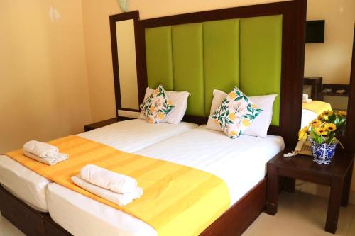 2 camas individuales en una habitación con paredes verdes en Riverside Regency Resort, en Baga