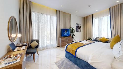 a bedroom with a bed and a desk and a television at SUHA Mina Rashid Hotel Apartments in Dubai