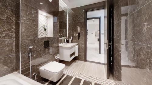 a bathroom with a toilet and a sink and a shower at SUHA Mina Rashid Hotel Apartments in Dubai
